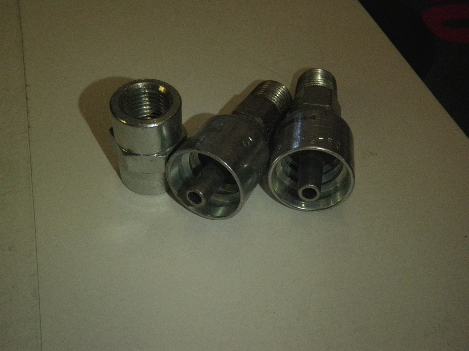 Three steel hydraulic quick couplers on a bench